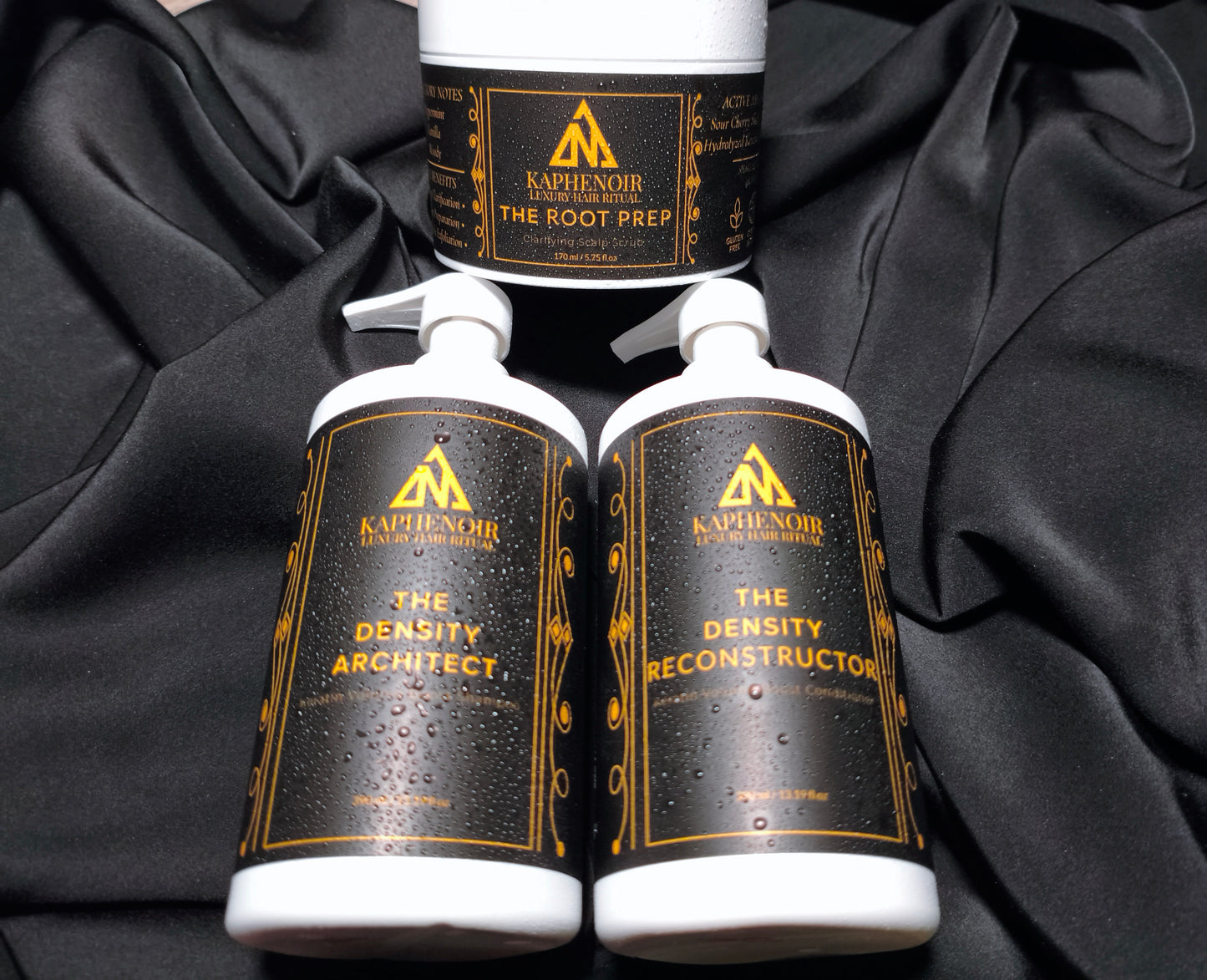 KapheNoir hair care bottles on black satin, featuring The Root Prep, Density Architect, Density Reconstructor.